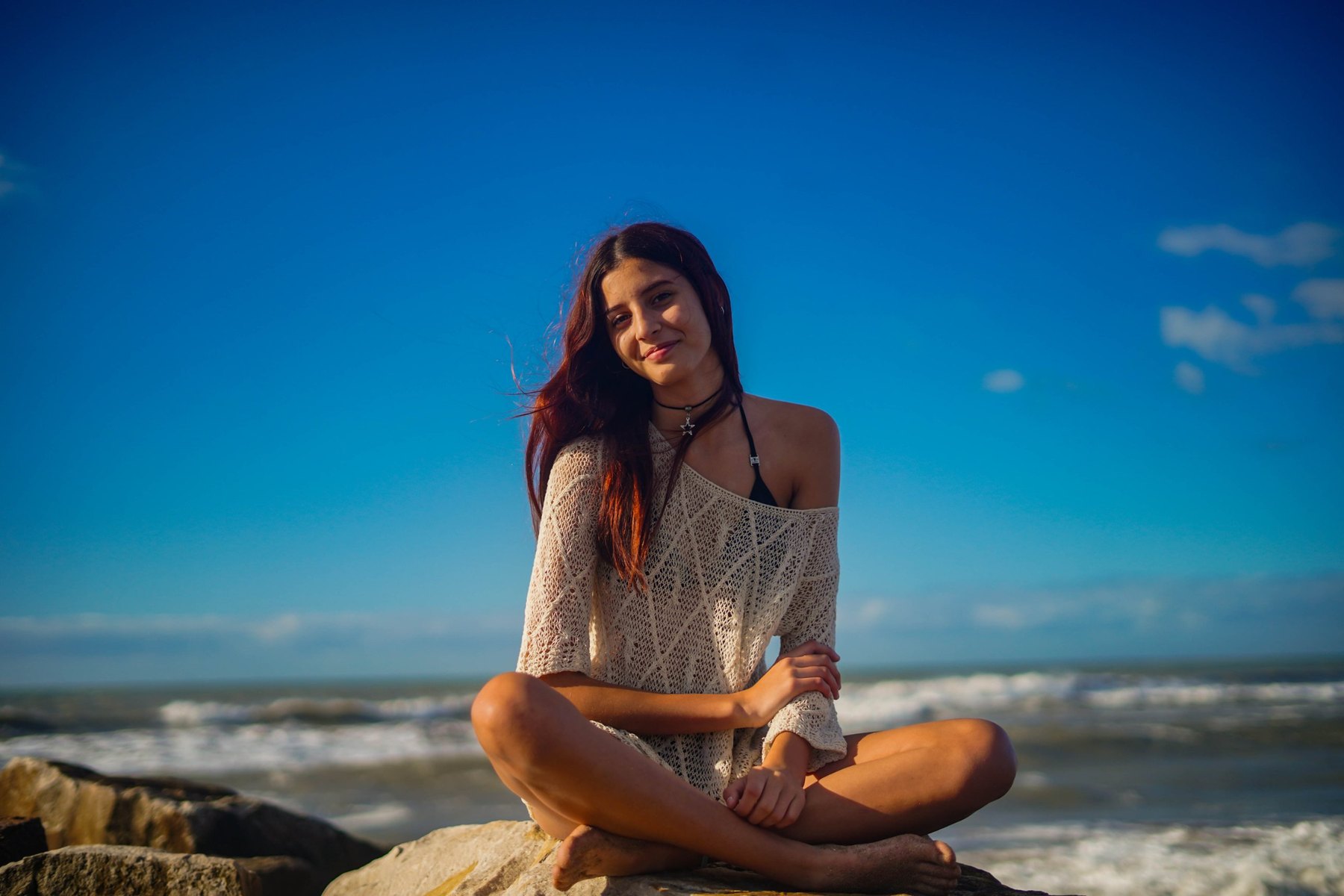 Delfina sentada sobre una roca frente al mar, sonriendo